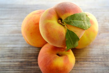 ahşap bir masa üzerinde yeşil yaprakları ile sağlıklı ve lezzetli şeftali