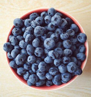 ahşap bir masa üzerinde bir kase lezzetli ve sağlıklı yaban mersini