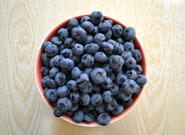 Välsmakande och hälsosamma blåbär i en skål på ett träbord — Stockfoto
