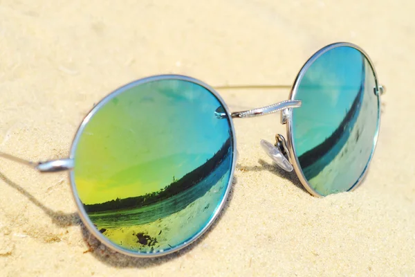 Gespiegelde zonnebril op zand met een weerspiegeling van het strand — Stockfoto