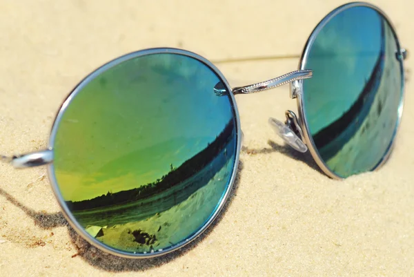 Spiegelnde Sonnenbrille auf Sand mit Spiegelung des Strandes — Stockfoto