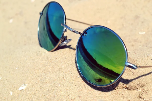 Зеркальные солнечные очки на песке с отражением пляжа — стоковое фото