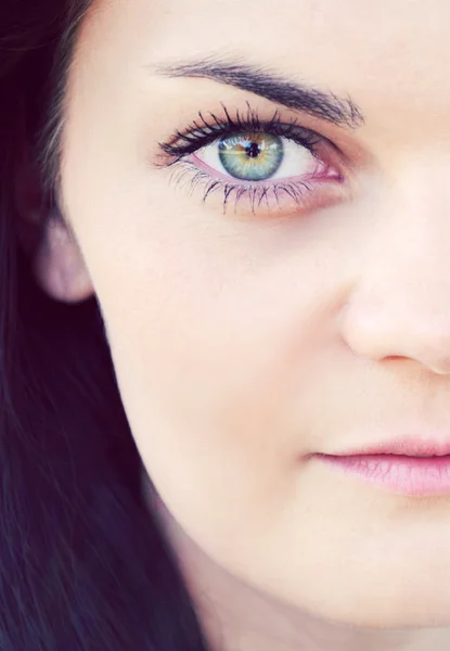 Junge und schöne brünette Frau mit leuchtend grünen Augen, die geheimnisvoll aussieht — Stockfoto