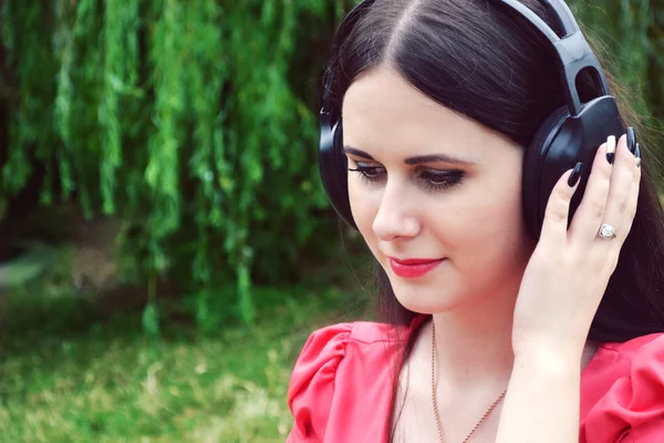 Wanita berambut cokelat cantik dengan headphone besar mendengarkan musik dengan senyum bahagia — Stok Foto