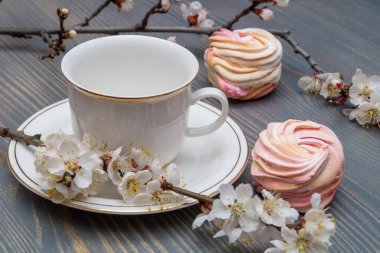 Çiçek açan dalların arasında beyaz bir porselen kapla narin beyaz-pembe şekerlemeler.