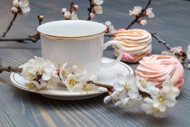 Çiçek açan dalların arasında beyaz bir porselen kapla narin beyaz-pembe şekerlemeler.