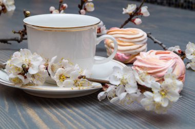 Çiçek açan dalların arasında beyaz bir porselen kapla narin beyaz-pembe şekerlemeler.