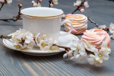 Çiçek açan dalların arasında beyaz bir porselen kapla narin beyaz-pembe şekerlemeler.