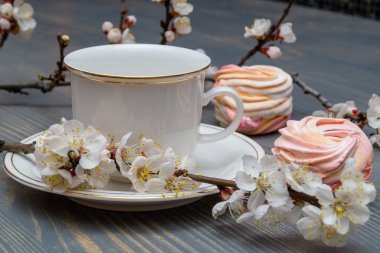 Çiçek açan dalların arasında beyaz bir porselen kapla narin beyaz-pembe şekerlemeler.