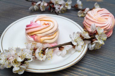 Beyaz porselen bir kapta, dalların arasında narin beyaz ve pembe şekerlemeler.