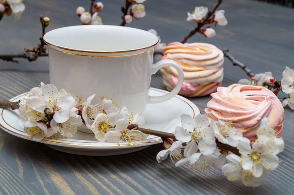 Çiçek açan dalların arasında beyaz bir porselen kapla narin beyaz-pembe şekerlemeler.