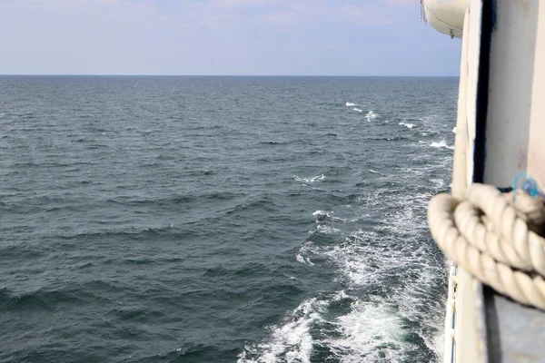 Stern waves with white foam tips on greyish blue sea water, photo taken from aboard ship. Selective focus