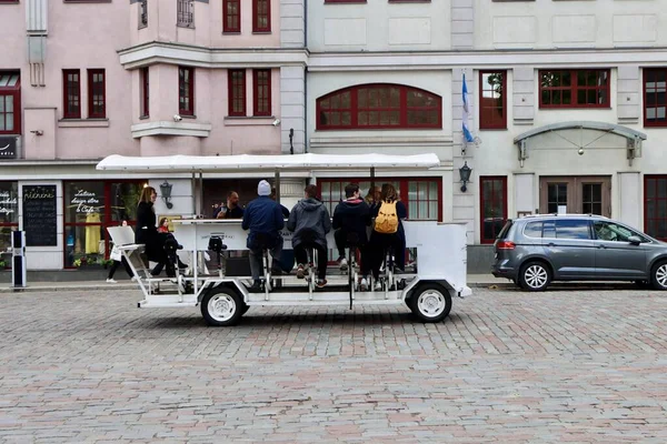 Turistler Litvanya 'nın Riga şehrinde kaldırımlı bir caddede gezici bir bira arabasıyla pedal çeviriyorlar - 28 Mayıs 2022
