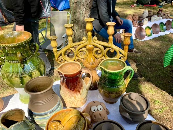 Merchandise on annual biggest crafts market in Latvian Ethnographic Open Air museum. Bright green traditional glazed ceramic vases, yellow candle holder. Riga, Latvia - June 4, 2022