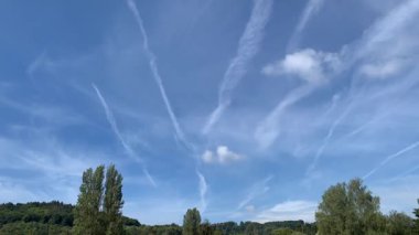 Time lapse of white contrails moving in wind over blue sky and small clouds forming after a long sunny spell and draught