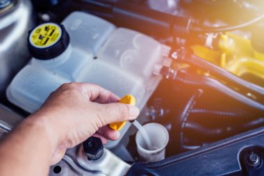 Depodaki su seviyesini kontrol etmek için ön cam yıkama sıvısı deposunun kapağını tutan adamın elini kapatın..