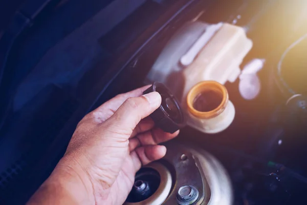 Bir motordaki fren yağı seviyesini kontrol ederken fren sıvısı deposunun kapağını tutan adamın el kapağını kapat 