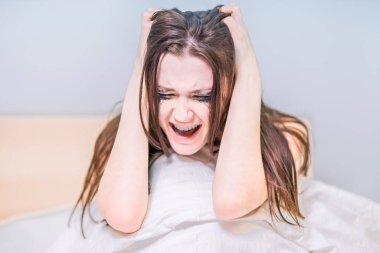 Maskaradan yüzü kirlenmiş bir kadın yatakta oturur ve ağlar ve çığlık atar. Kötü haberi al. Sinirlen. Acı çekmek için. Depresyon. Kalbi kırılmış. Kırık kalp.