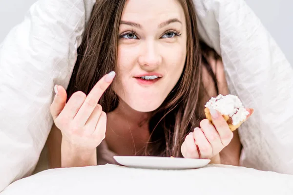 Kalorie Deser Urocza Kobieta Trzyma Babeczkę Dłoniach Leżąc Łóżku Pod — Zdjęcie stockowe