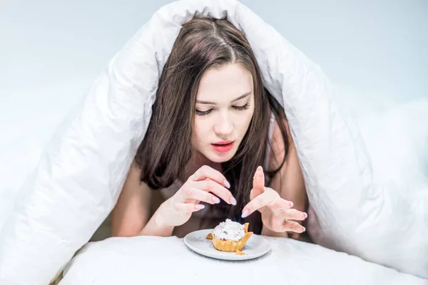 Słodka Kobieta Leżąca Łóżku Pod Kołdrą Spójrz Babeczkę Śniadanie Łóżka — Zdjęcie stockowe