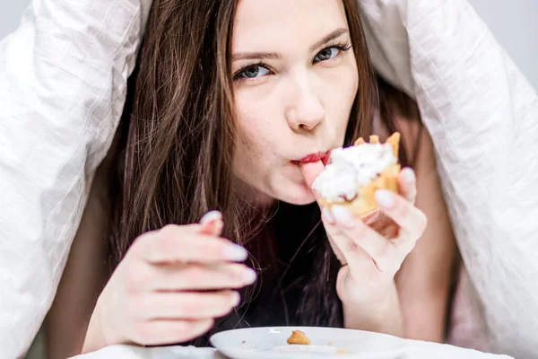 Leuke Vrouw Eet Een Cupcake Liggend Het Bed Onder Dekens — Stockfoto