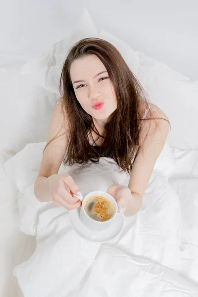 Una Donna Siede Letto Beve Caffè Aromatico Sorride Manda Bacio Fotografia Stock