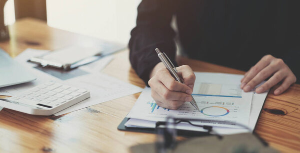 Business woman using calculator for do math finance on wooden desk in office and business working background, tax, accounting, statistics and analytic research concep