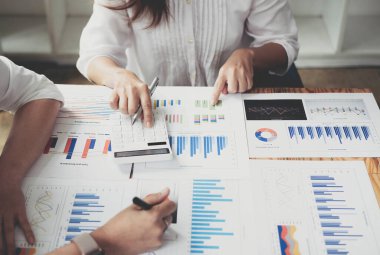 Finans, vergi, muhasebe, istatistik ve analitik araştırma konseptini hesaplamak için hesap makinesi ve dizüstü bilgisayar kullanarak iş adamı ve ortağını kapat