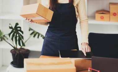 Genç Asyalı kadın eve nakliye siparişini kontrol ediyor, iş sahibi kadın internet üzerinden iş kuruyor, KOBİ, Teslimat Projesi, Çevrimiçi iş yapan kadın veya KOBİ uzmanı