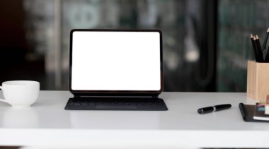 Laptop, dizüstü bilgisayar, kahve fincanı ve ahşap masadaki kırtasiye malzemeleriyle çağdaş işyerinin yan görüntüsü