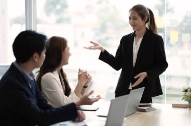 Güzel iş adamları konferans sırasında ofis aletleri kullanıyor, konuşuyor ve gülümsüyor.