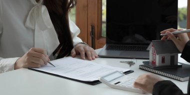 Emlakçı ve müşteriyle ev modeli satın alma, sigorta ya da kredi alma ya da emlak ya da mülkiyet sözleşmesi hakkında tartışıyor