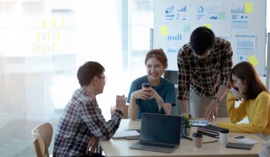 Girişim ekibi modern parlak ofis içinde toplantı ve lapto üzerinde çalışıyor