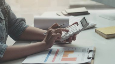 Hesap makinesi, iş belgesi ve dizüstü bilgisayarla çalışan kadını kapat