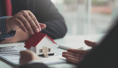 Emlakçı ev tasarımını ve satın alma anlaşmasını görmeye gelen müşterilere ev tarzını anlatıyor. Modern bir ofisin içinde