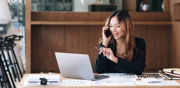 Asian business woman have the joy of talking on the phone, laptop and tablet on the office desk
