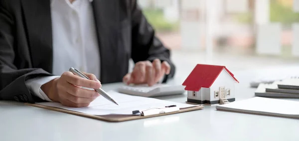 Finans bütçesi, kredi belgesi ve evin fiyatını hesaplamak için hesap makinesiyle ofis masasında çalışan işadamı ya da banka memuru. Emlakçı ve ev kredisi konsepti