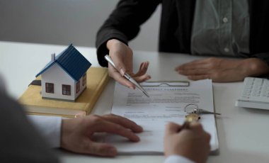Emlakçı ya da satış müdürü, ev satın alma anlaşmalarını sigorta ile imzalayan müşterilere satın alma sözleşmesini imzalama şartlarını ve şartlarını önerdi.