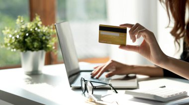 Bilgisayardan online sipariş detaylarını kontrol eden Asyalı bir kadın ve bilgisayardan girilen kredi kartı bilgilerini kullan