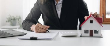 Kadın eli ev modelini tutuyor, küçük minyatür beyaz oyuncak evi. Ev kredisi sigortası hayali eve taşınmak ve gayrimenkul danışmanlığı