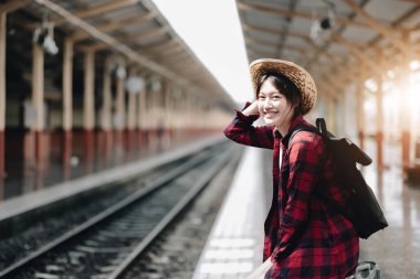 Young traveler woman looking for friend planning trip at train station. Summer and travel lifestyle concep