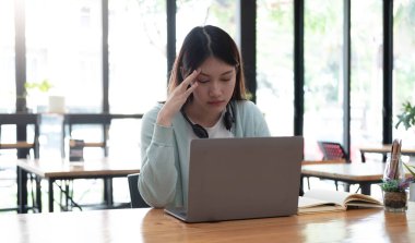 Ciddi odaklı Asyalı öğrenci mutfakta dizüstü bilgisayar kullanıyor, dikkat ve konsantrasyonla ekrana bakıyor, webinar öğrenme, sanal eğitim, video kursu, evden ders çalışıyor.