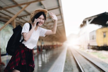 Young traveler woman looking for friend planning trip at train station. Summer and travel lifestyle concep