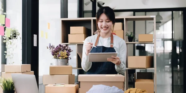 Small start-up business owners using computers at work, freelancers, saleswoman, checking production orders. Pack products for delivery to customers sell ecommerce delivery idea