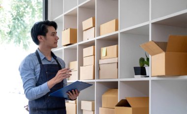 Küçük işletme sahibi iş yerindeki karton kutuya adres yazıyor. Küçük işletme girişimcisi KME, evdeki kutuyla çalışıyor, çevrimiçi satıyor, e-ticaret yapıyor, paketliyor.