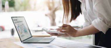 Asian female accountant or banker making calculations. Savings, finances and economy concept through a laptop