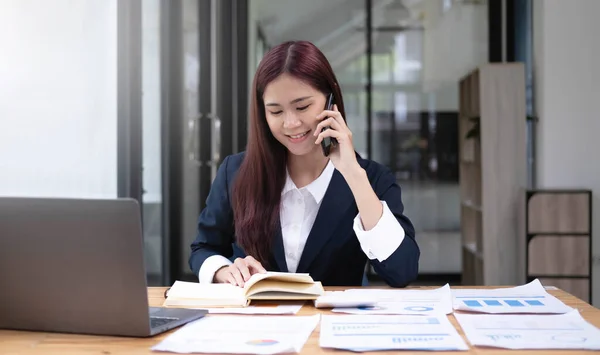 Asian business woman have the joy of talking on the phone, laptop and tablet on the office desk