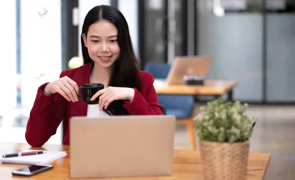 Young asian businesswoman have the pleasure of watching work on their tablet and favorite coffee at the office