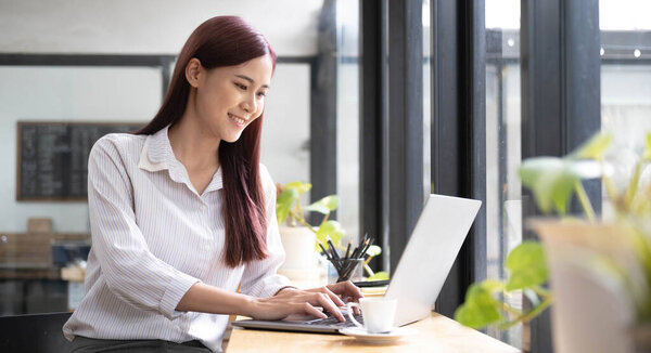 Close up portrait of a beautiful young Asia woman smiling and looking at laptop scree