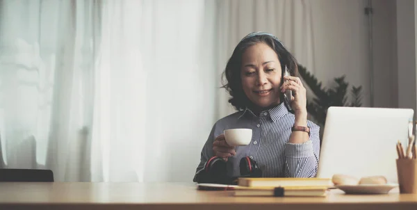 Happy pretty mature woman speaking on mobile phone portrait. Senior grey haired lady making telephone call, sitting on couch at home, enjoying talk, communication